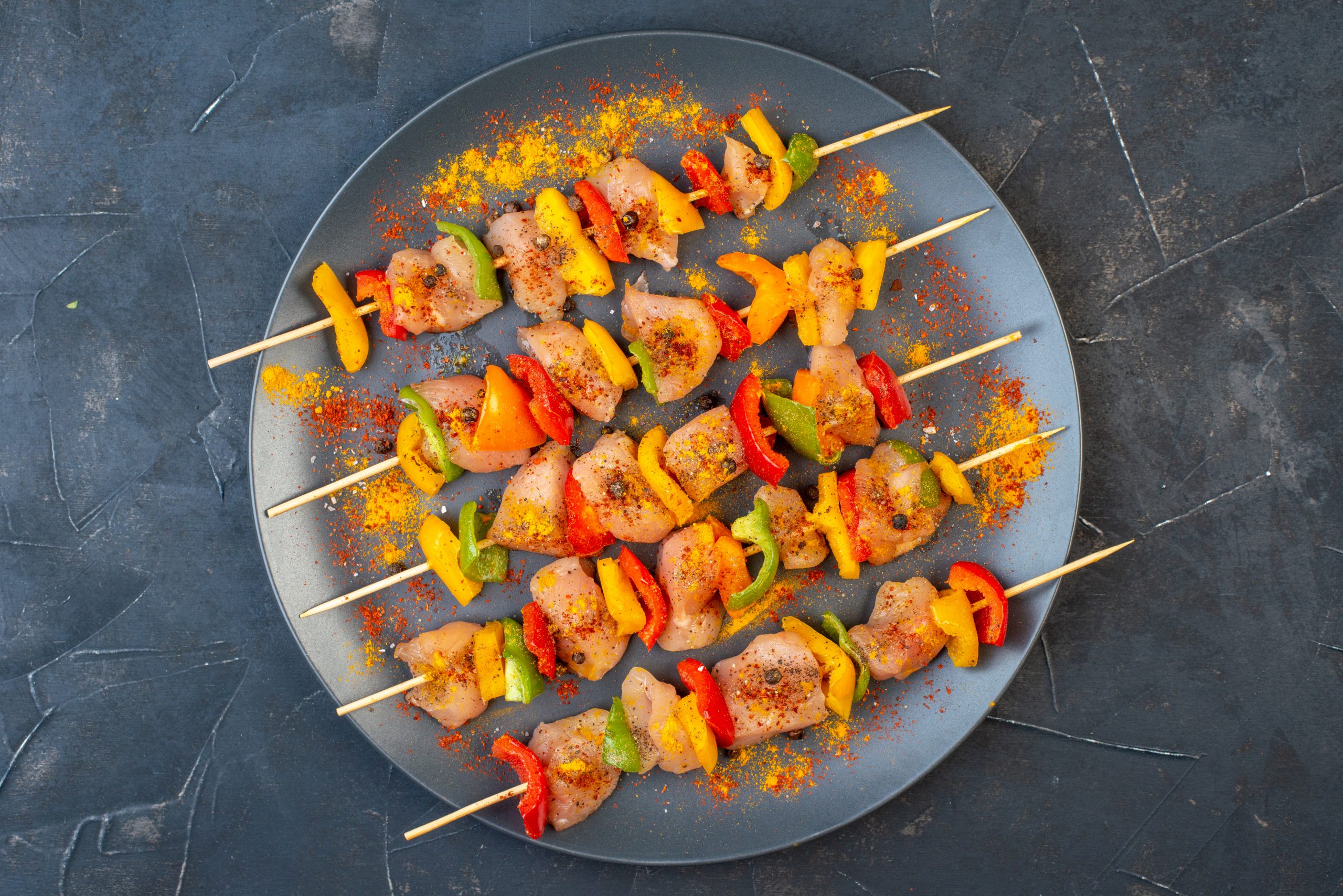 top-view-raw-chicken-skewers-with-spices-wooden-board-dark-table